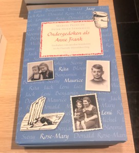 A book with the title, "Ondergedoken als Anne Frank: tales of Jewish children in hiding." The cover features black and white photos of several children.